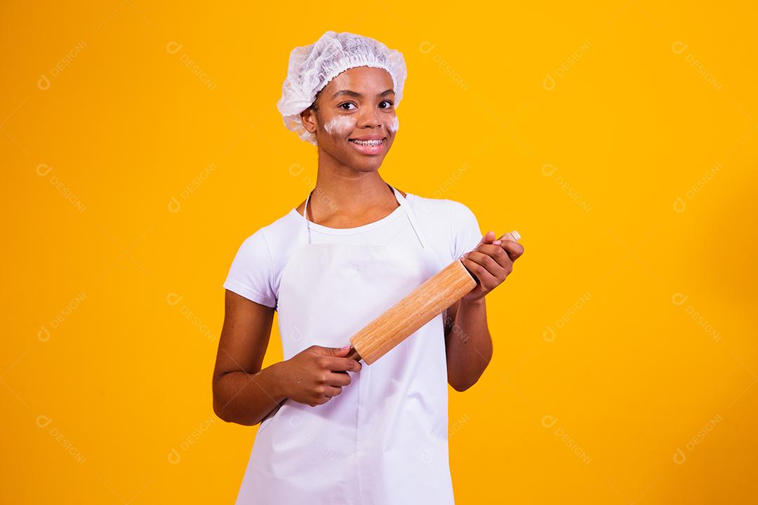 Fabricante de pizza jovem em fundo amarelo, segurando o rolo.