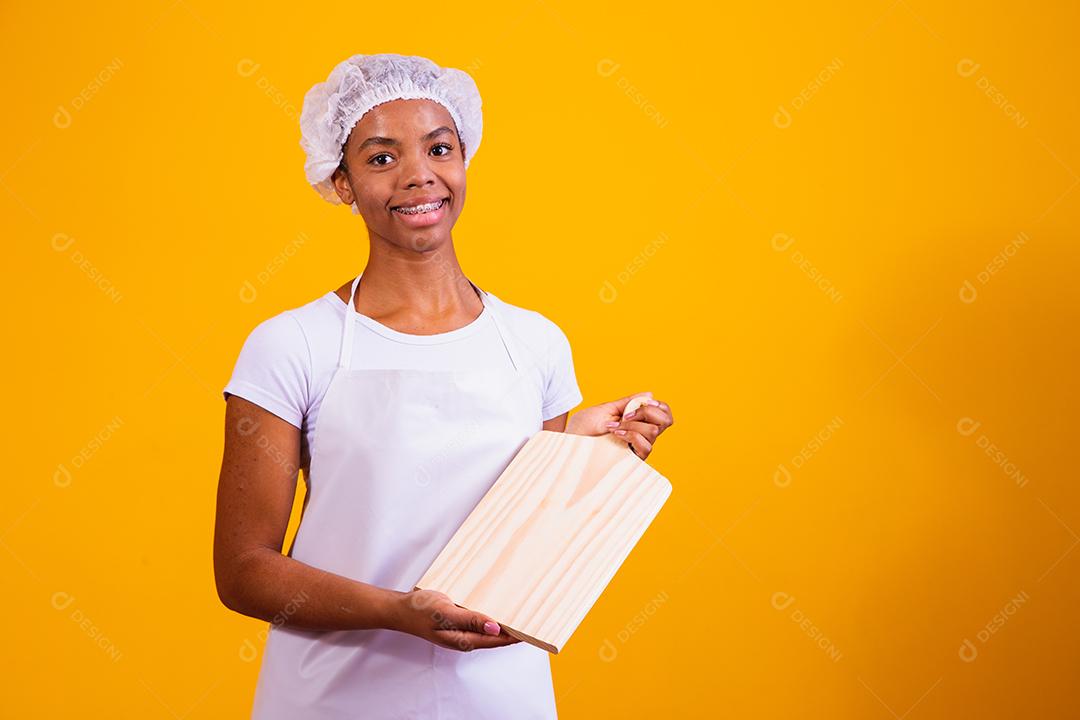 Mulher Com roupa de cozinheira e taboa de corte na mão em fundo amarelo