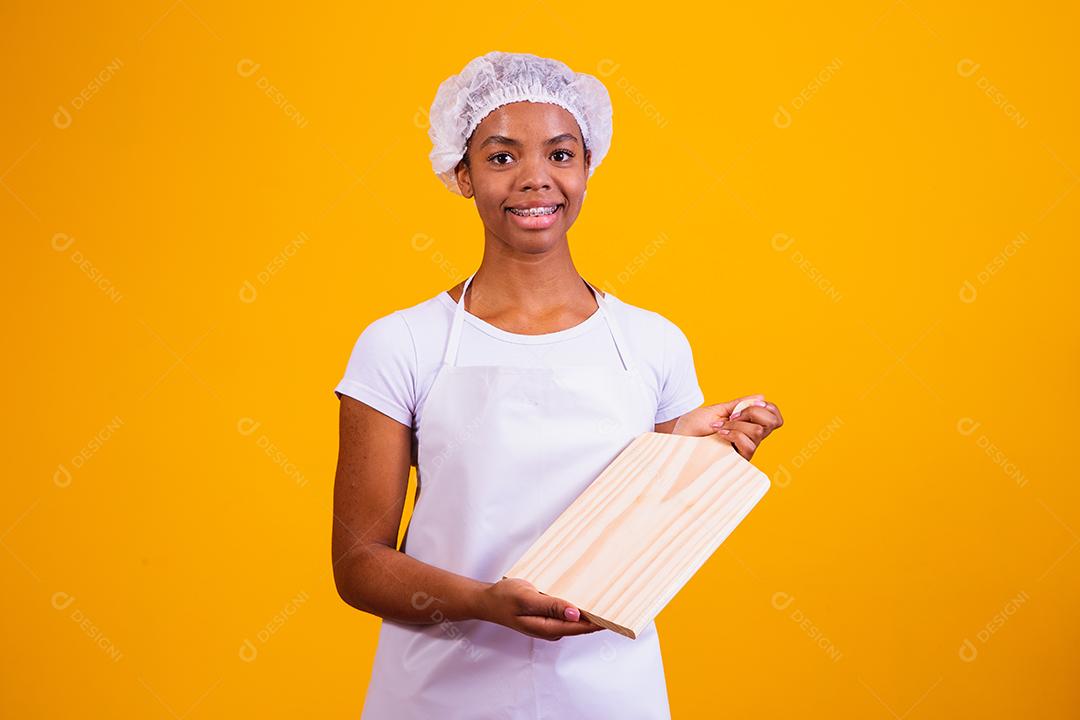 Mulher Com roupa de cozinheira e taboa de corte na mão em fundo amarelo
