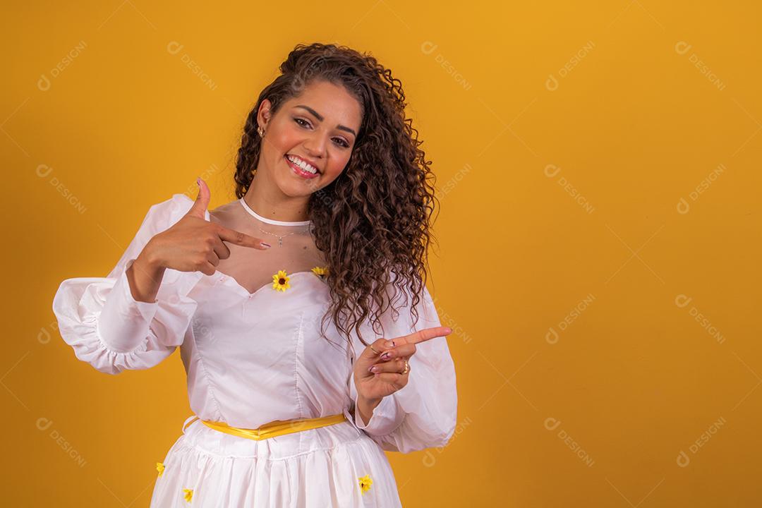 jovem afro vestida para festa junina apontando