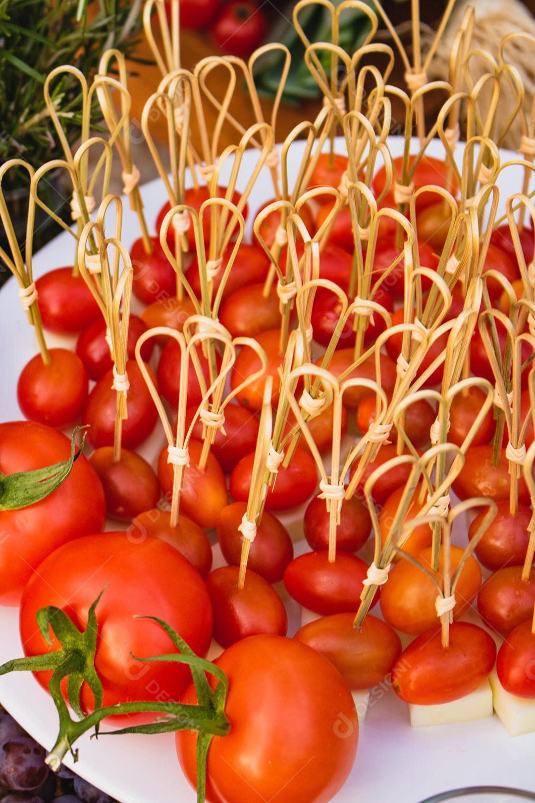 Prato com vários tomates espetados com queijo acima de mesa