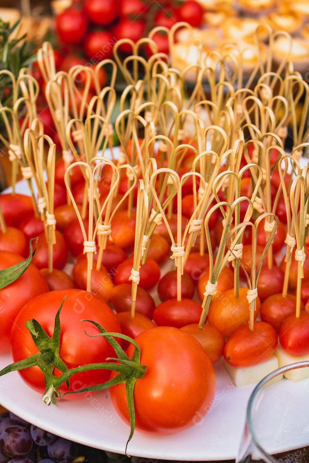 Prato com vários tomates espetados com queijo acima de mesa