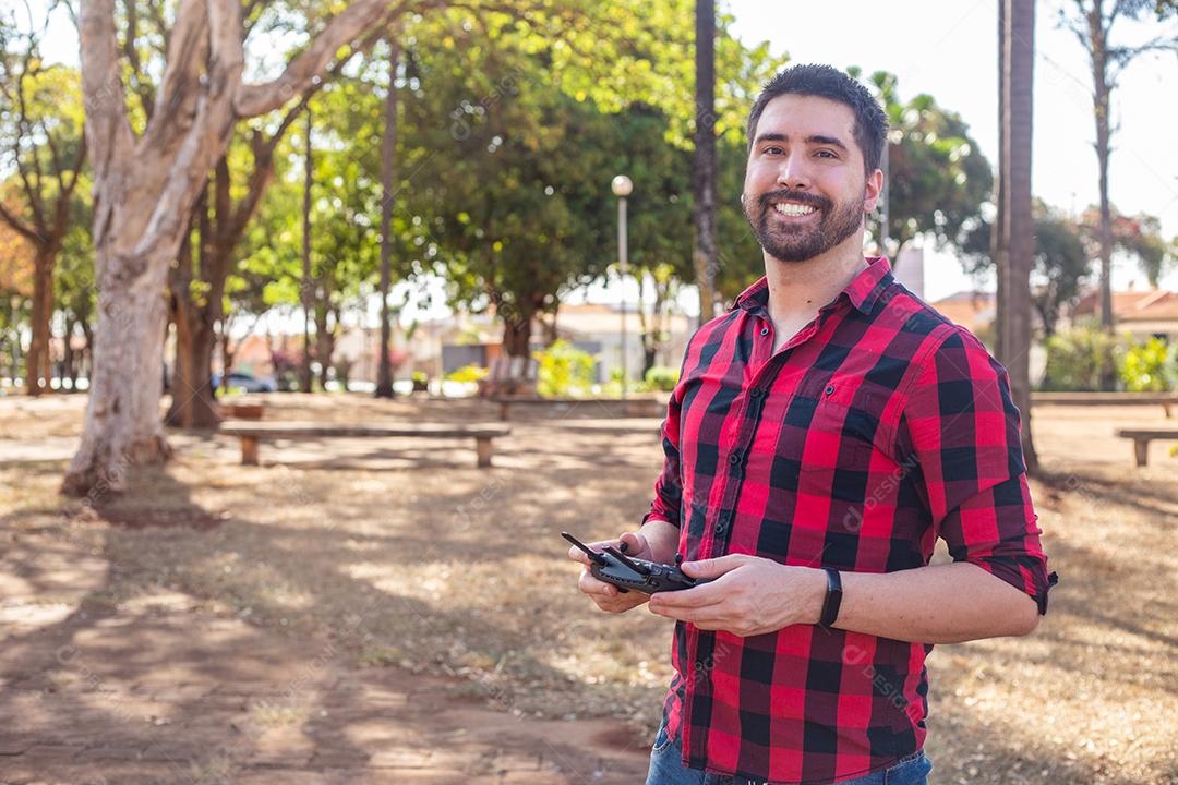 Homem com camisa xadrez segurando controle de drone imagem JPG
