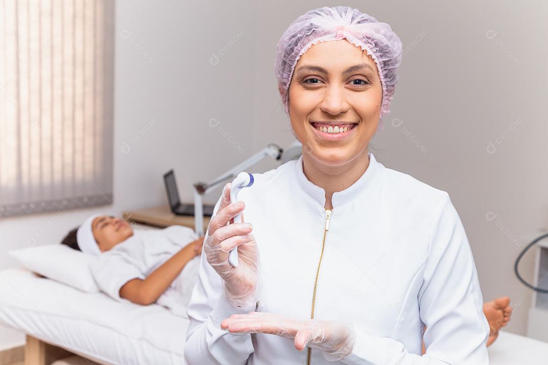 closeup na esteticista segurando microagulhamento sorrindo para uma câmera