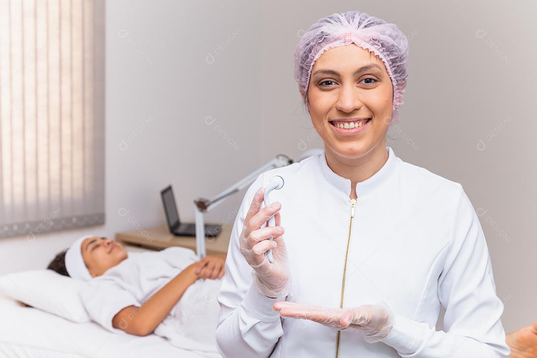 closeup na esteticista segurando microagulhamento sorrindo para uma câmera