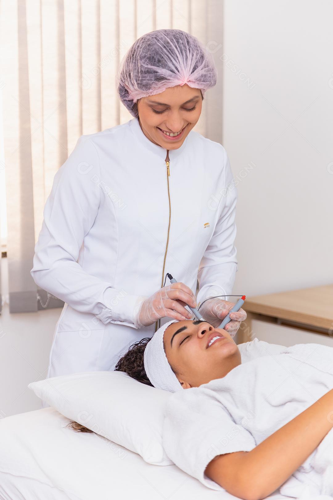 Jovem deitada na mesa do cosmetologista durante o procedimento de rejuvenescimento. Cosmetologista cuida da pele do pescoço