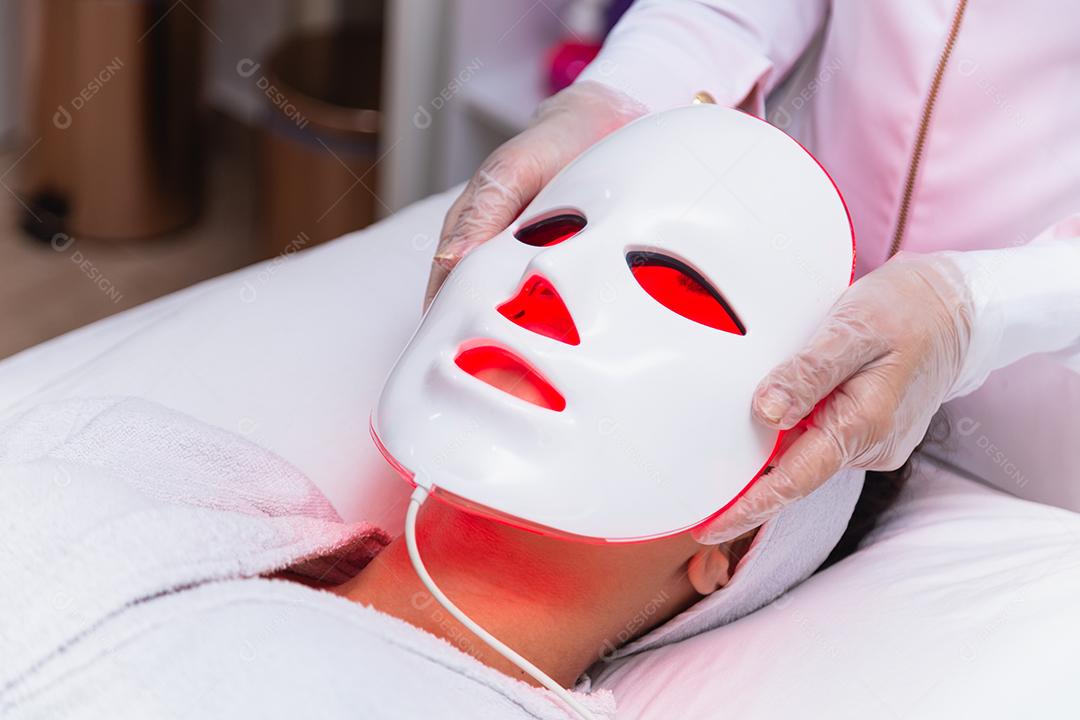 Máscara facial de terapia fotodinâmica no rosto da mulher