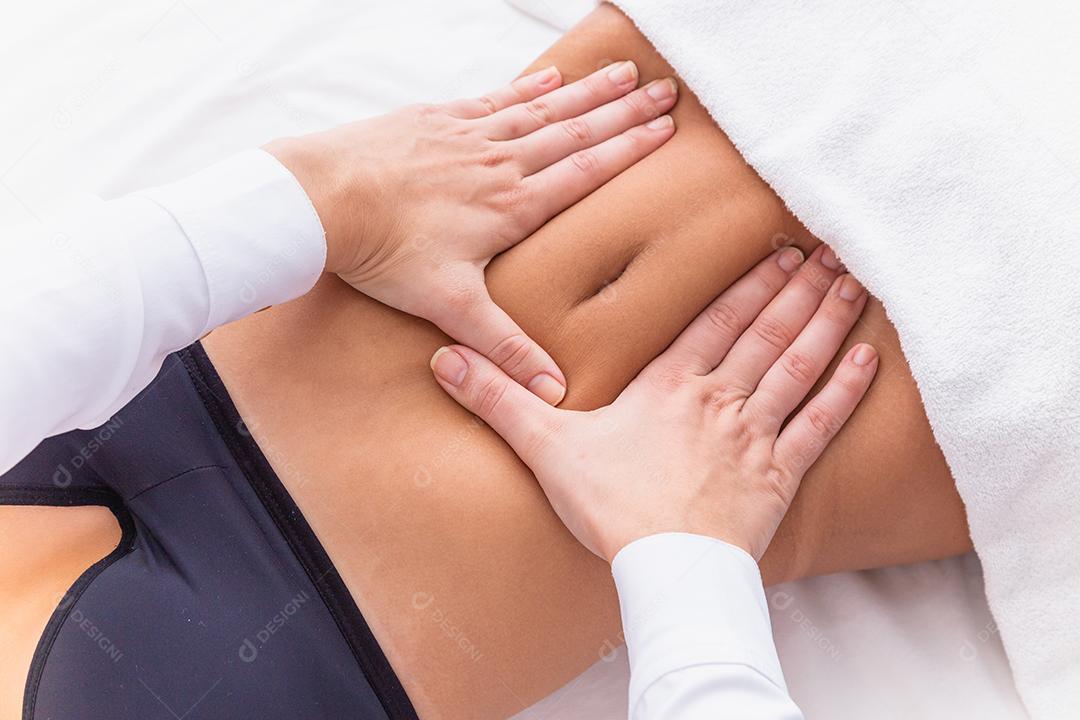 mulher fazendo massagem de modelagem na barriga dela.