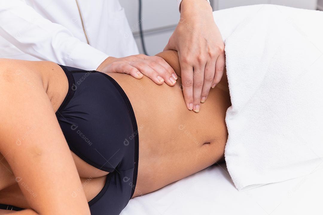 mulher fazendo massagem de modelagem na barriga dela.