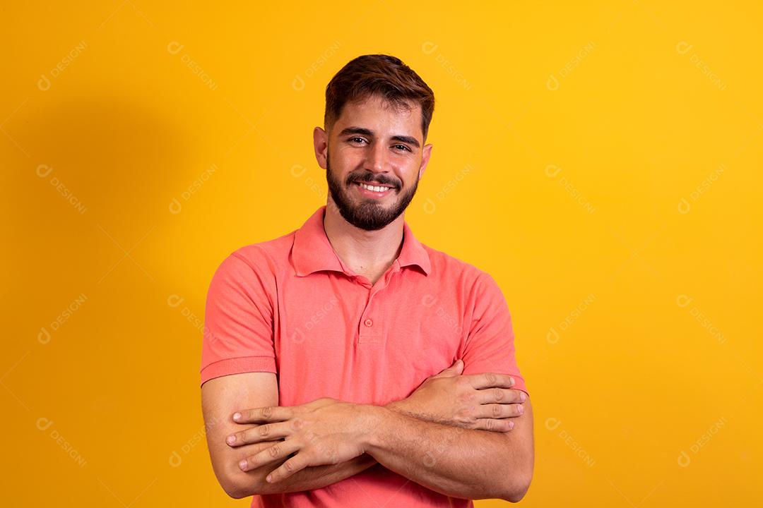 Menino com os braços cruzados sorrindo em fundo amarelo