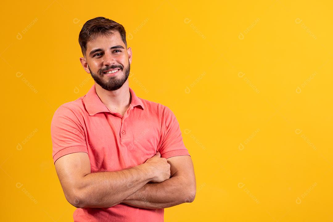 Menino com os braços cruzados sorrindo em fundo amarelo