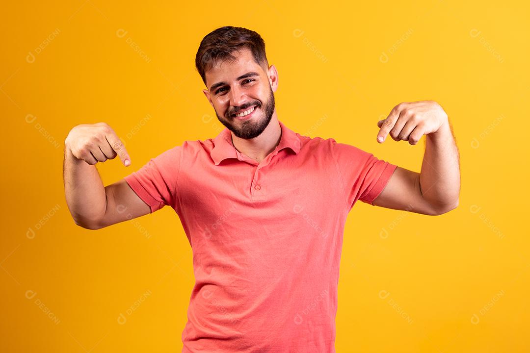 Menino sorrindo para a câmera apontando para baixo com o conceito aqui.