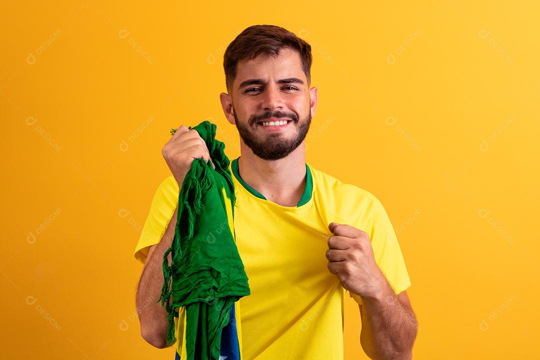fã brasileiro torcendo no meio da multidão em fundo amarelo.