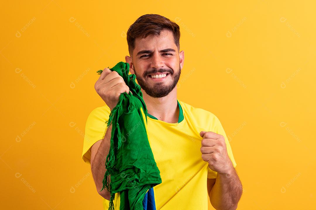 fã brasileiro torcendo no meio da multidão em fundo amarelo.