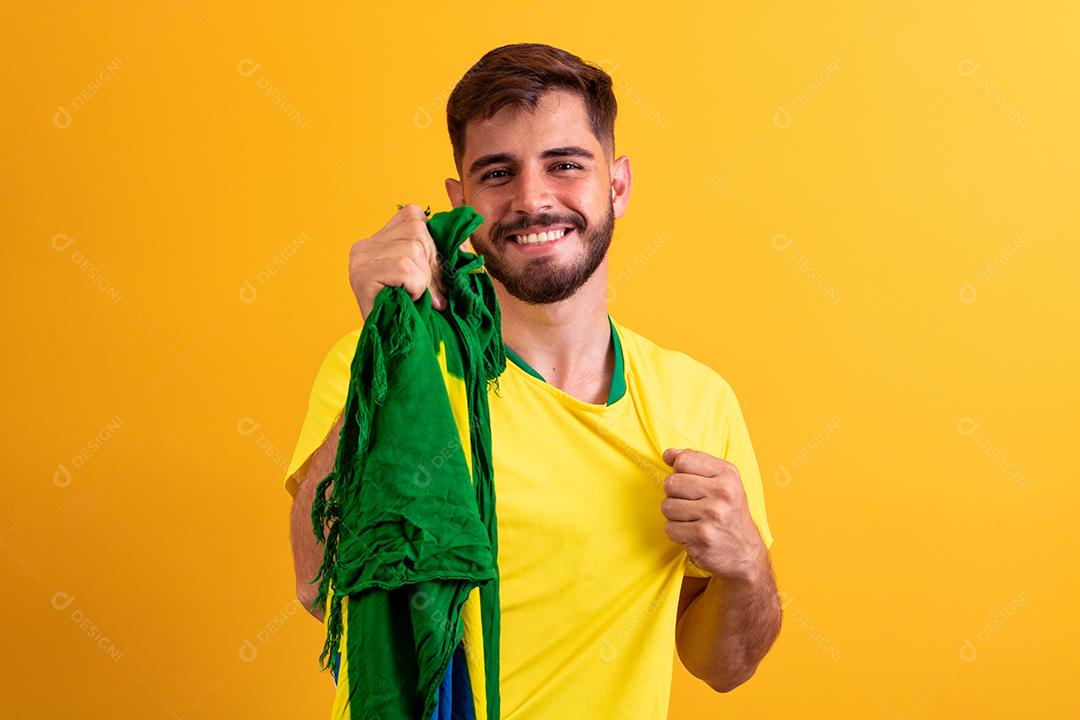 fã brasileiro torcendo no meio da multidão em fundo amarelo.