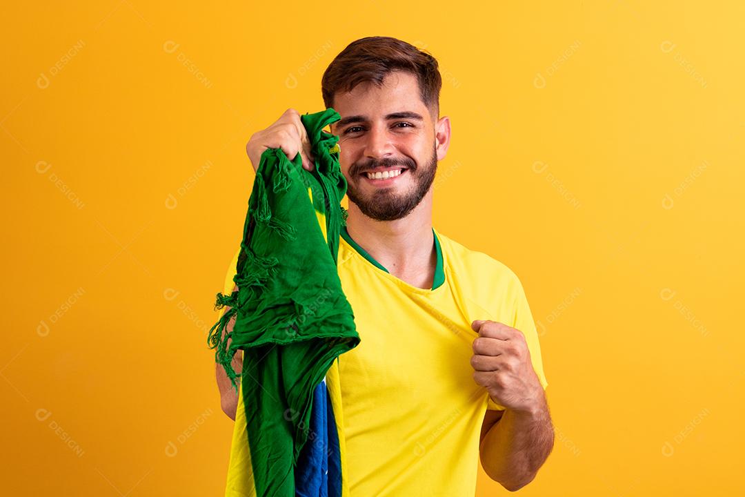 fã brasileiro torcendo no meio da multidão em fundo amarelo.