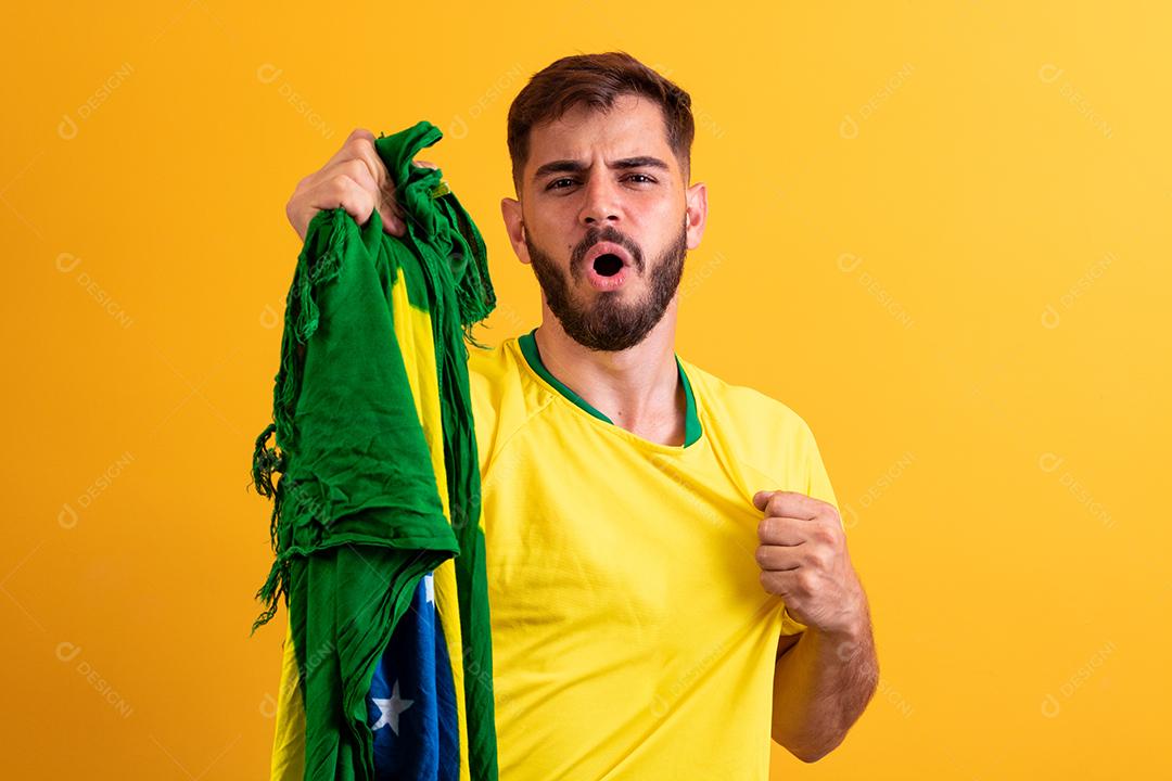 fã brasileiro torcendo no meio da multidão em fundo amarelo.