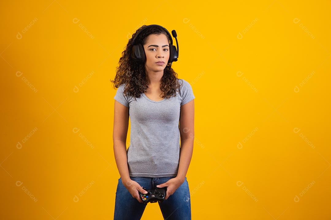 Mulher excitada jogando videogame em fundo amarelo.