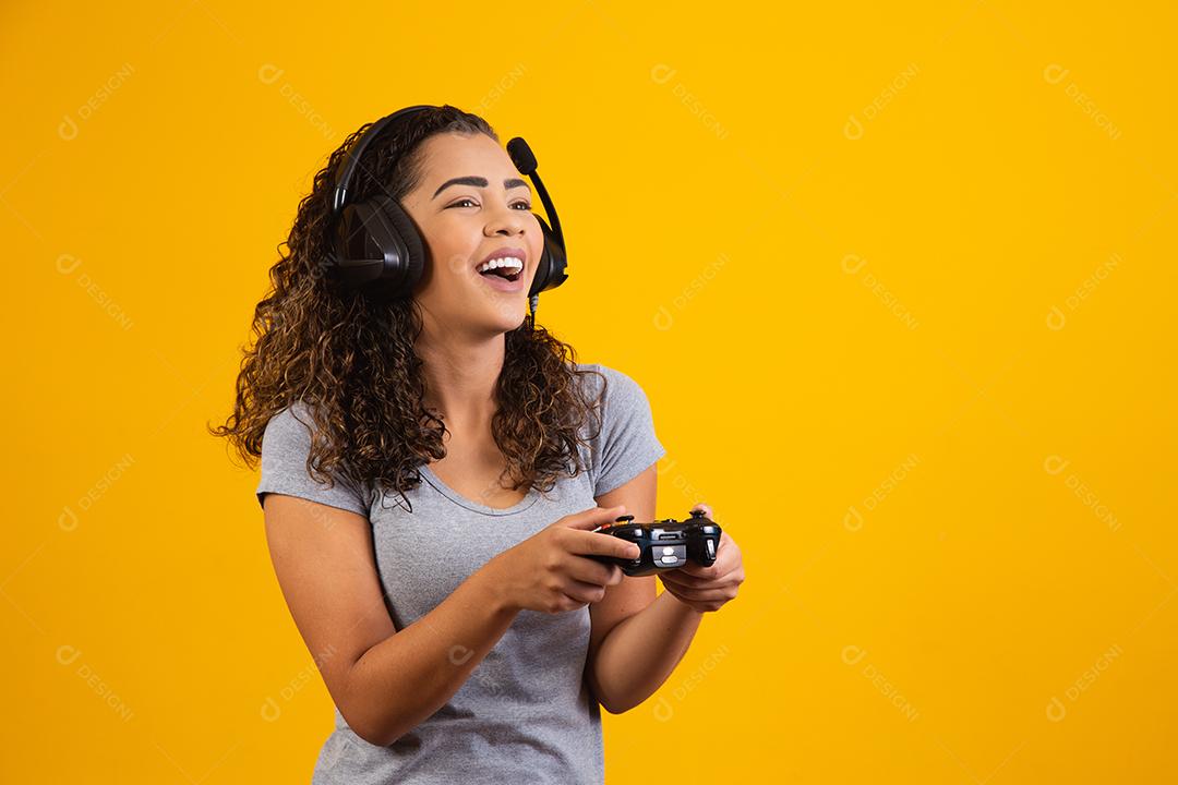 Mulher excitada jogando videogame em fundo amarelo