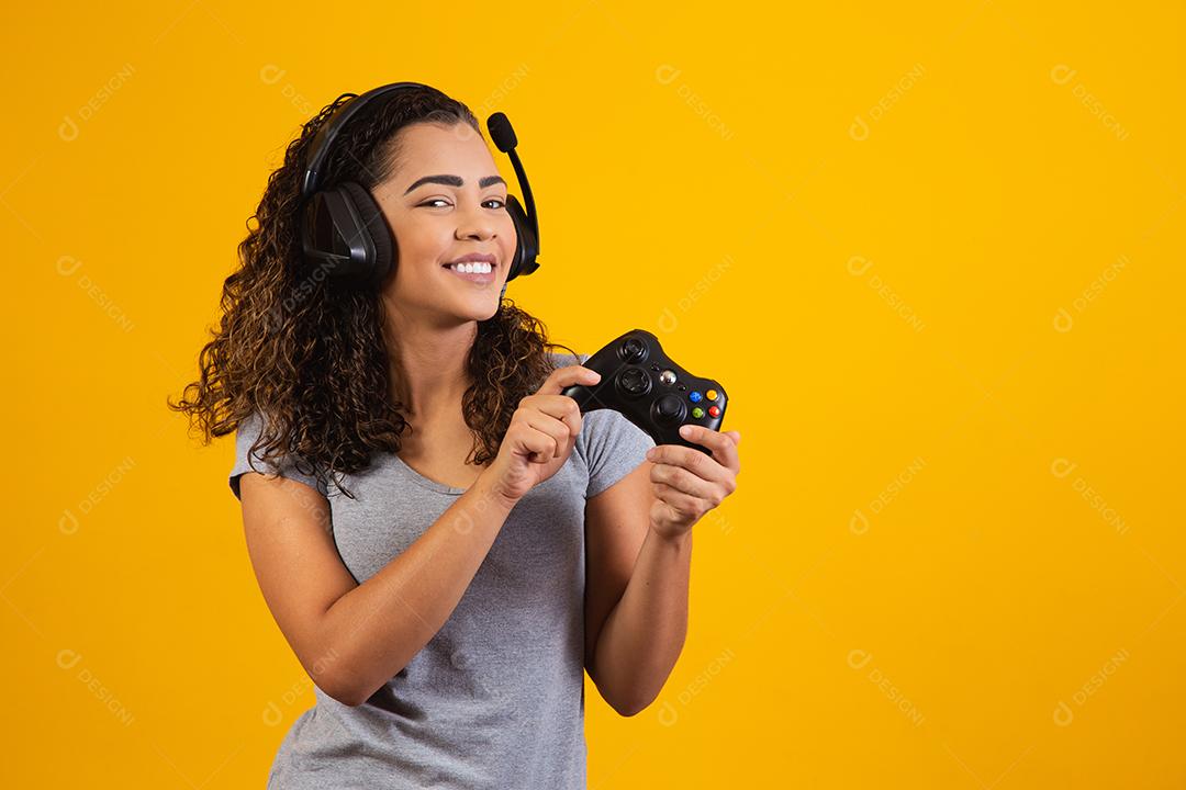 Mulher excitada jogando videogame em fundo amarelo