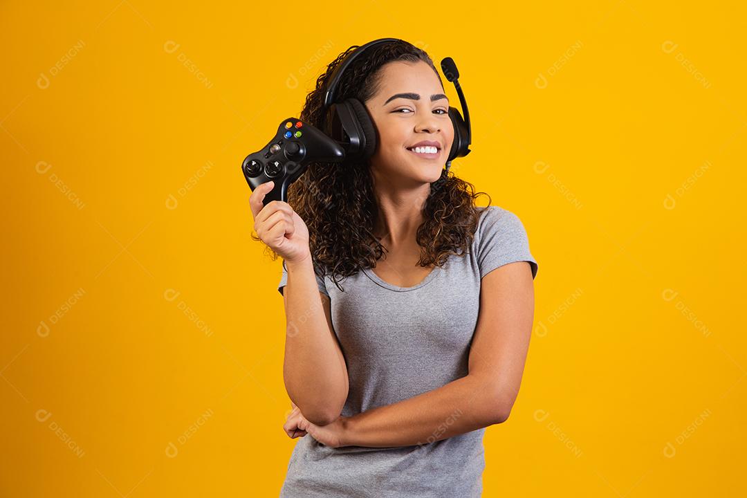 Mulher excitada jogando videogame em fundo amarelo.