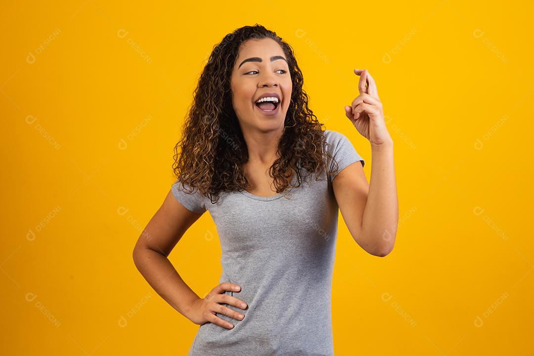 mulher afro com os dedos cruzados torcendo pela vitória