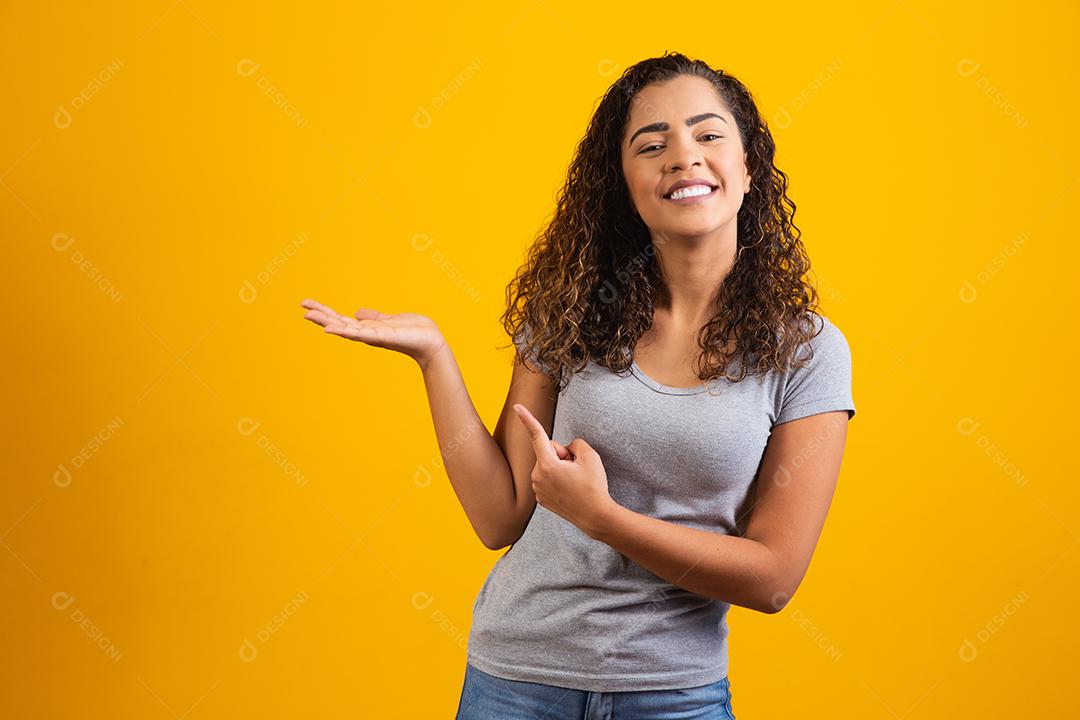 Mulher afro apontando em fundo amarelo com espaço para o texto