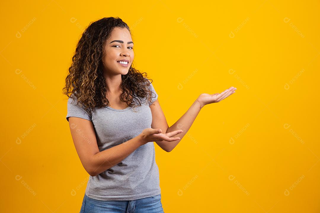 Mulher afro apontando em fundo amarelo com espaço para o texto
