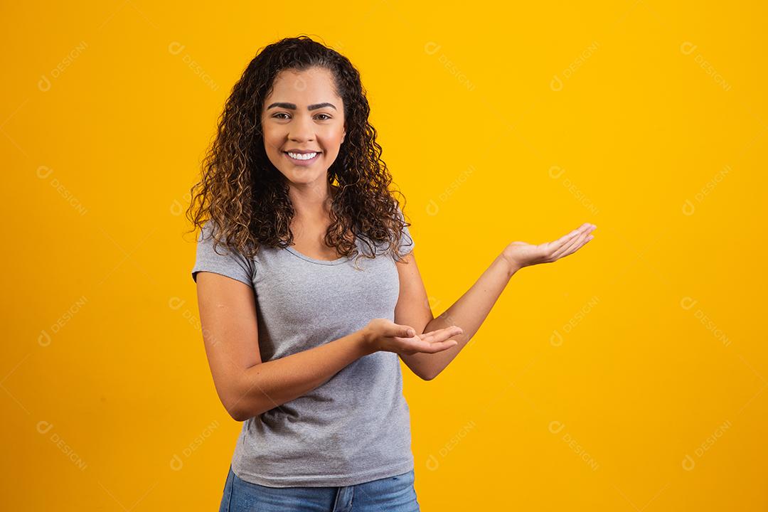 Mulher afro apontando em fundo amarelo com espaço para o texto