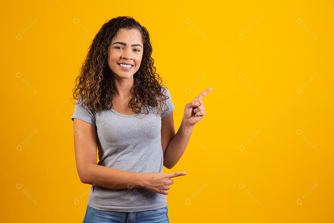 Afro woman pointing on yellow background with space for text