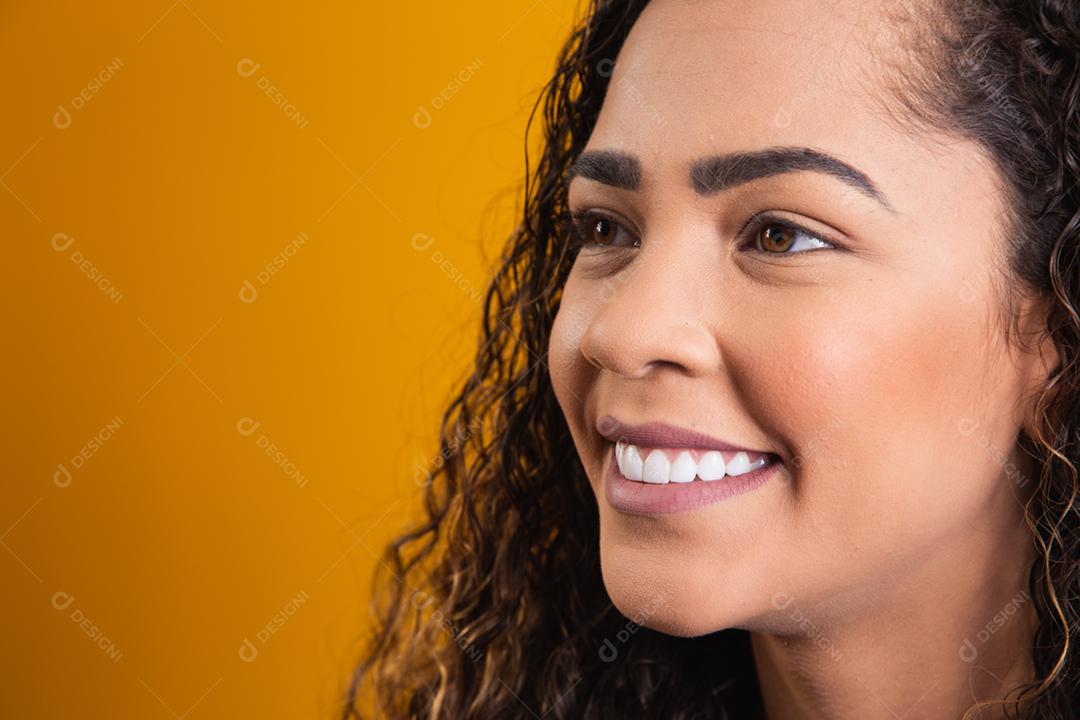 closeup no rosto de mulher afro sorrindo em fundo amarelo
