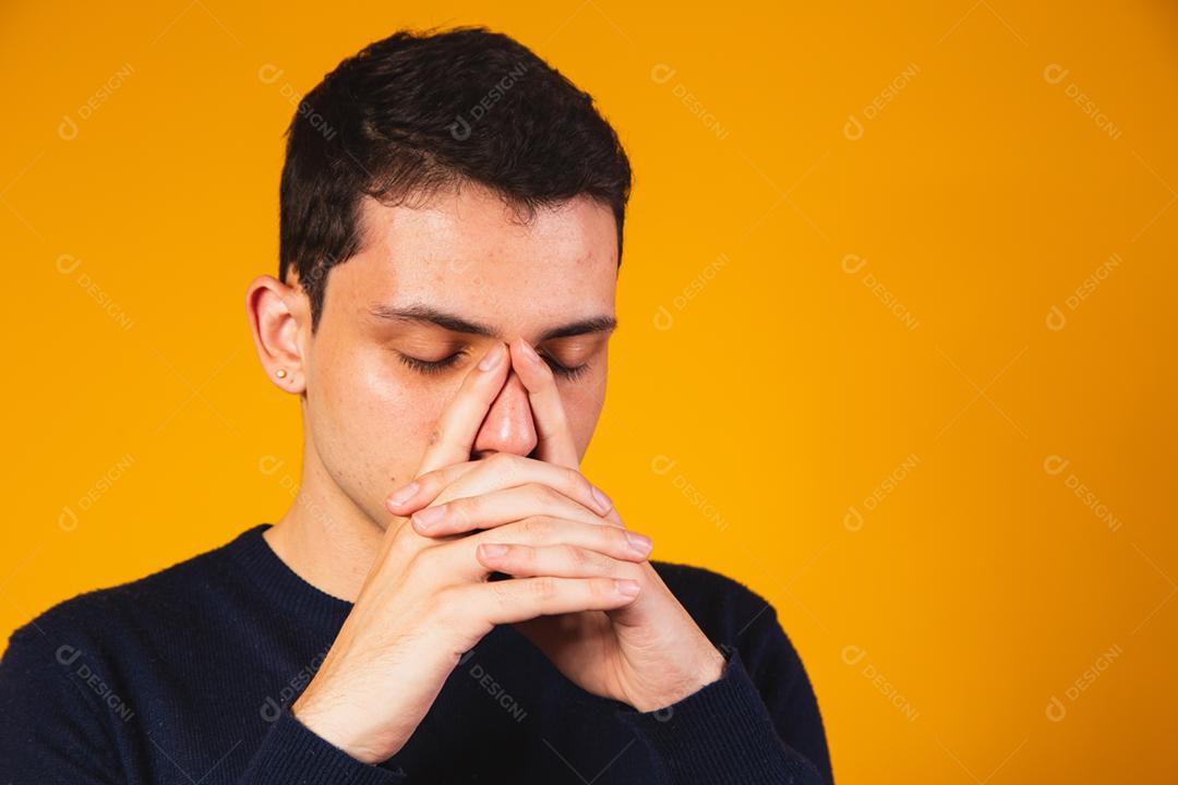 Rapaz nervoso rezando sobre fundo amarelo. menino angustiado falando