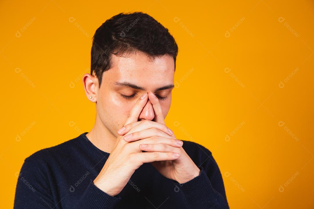 Rapaz nervoso rezando sobre fundo amarelo. menino angustiado falando