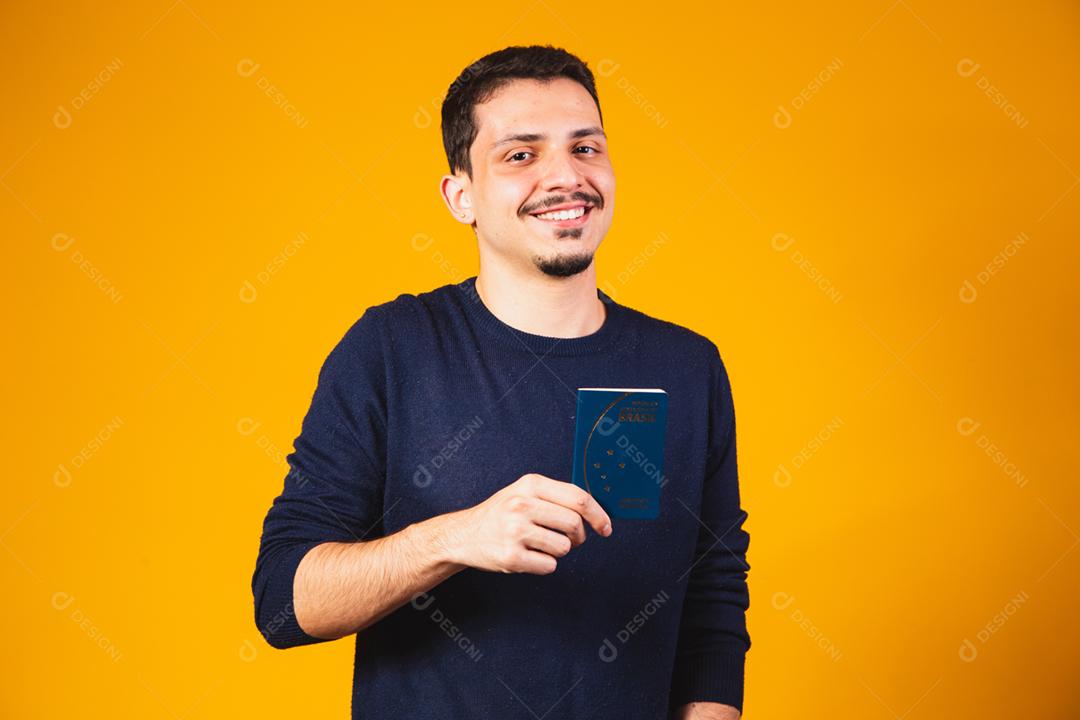 Retrato de um homem segurando um passaporte brasileiro nas mãos.
