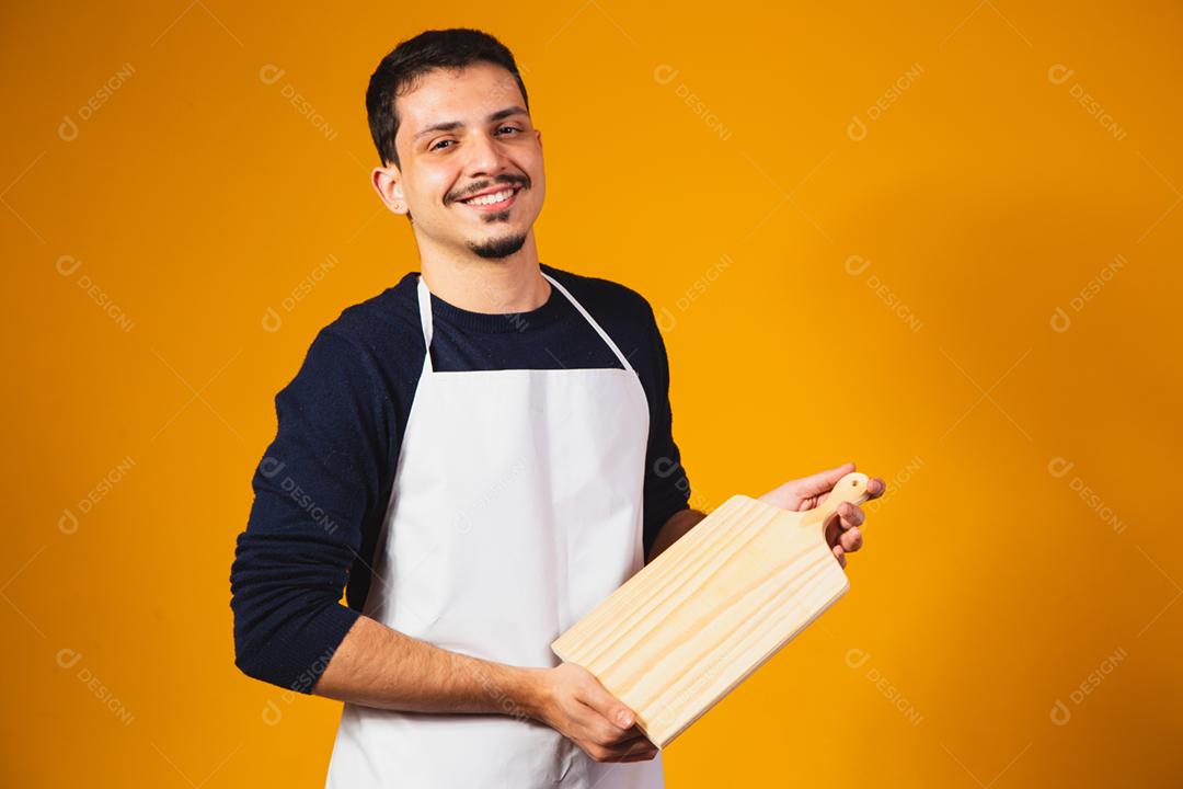 homem de avental branco, segurando uma tábua de cortar.