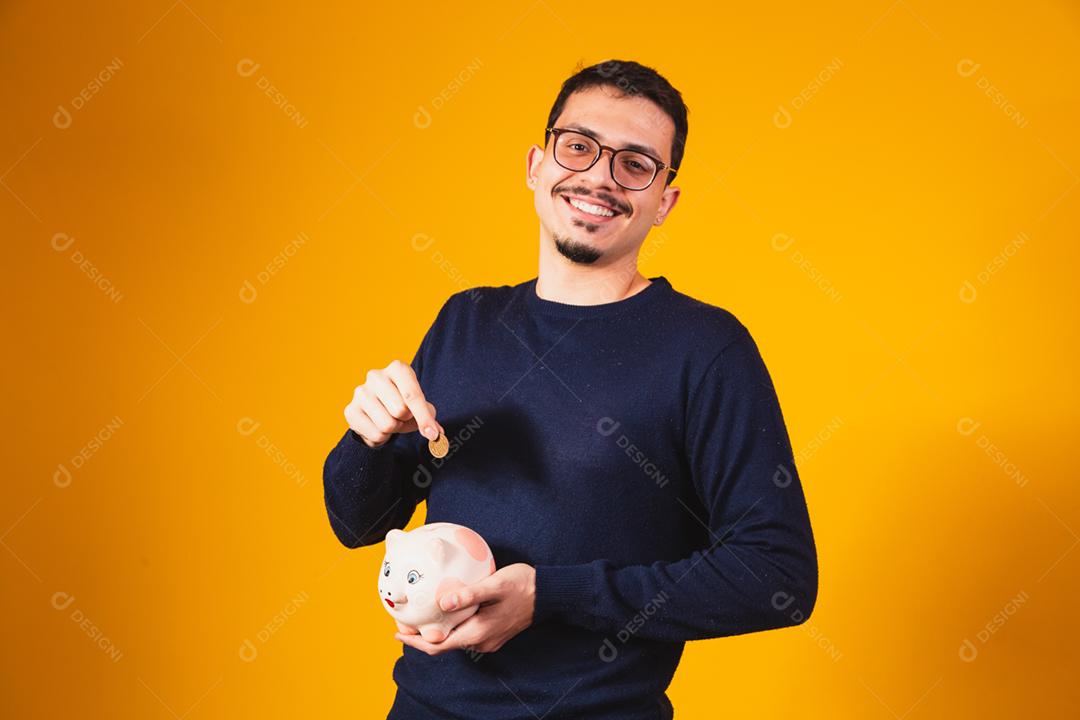 Empresário economizando dinheiro colocando moedas no cofrinho.