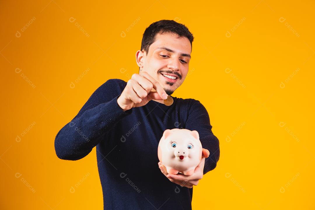 Empresário economizando dinheiro colocando moedas no cofrinho.