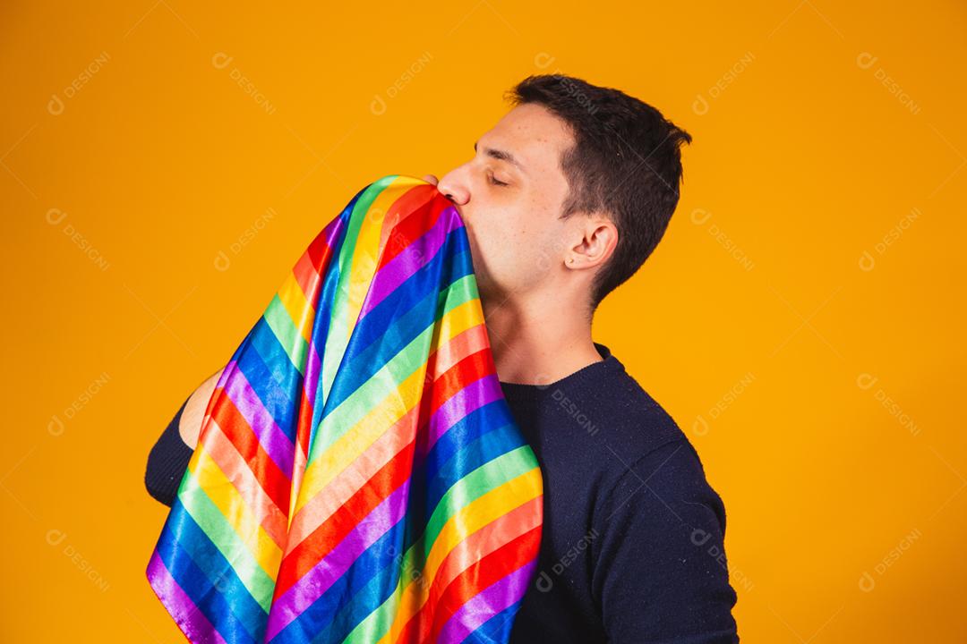 Orgulho gay. Garoto homossexual beijando bandeira lgbt em fundo amarelo