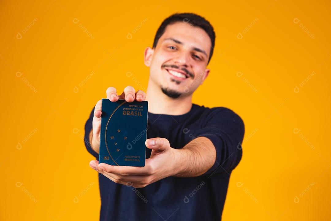 Retrato de um homem segurando um passaporte brasileiro nas mãos.