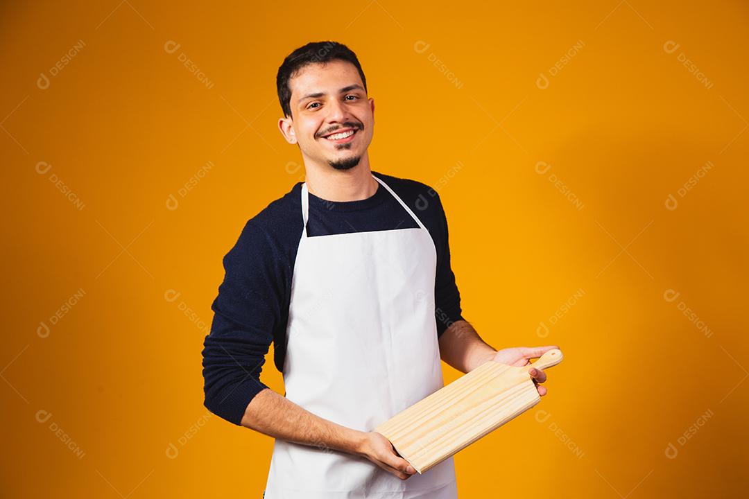 homem de avental branco, segurando uma tábua de cortar.