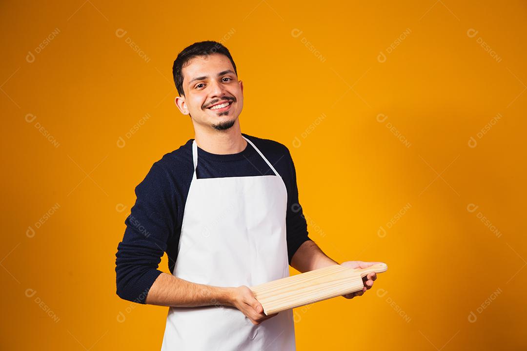 homem de avental branco, segurando uma tábua de cortar.