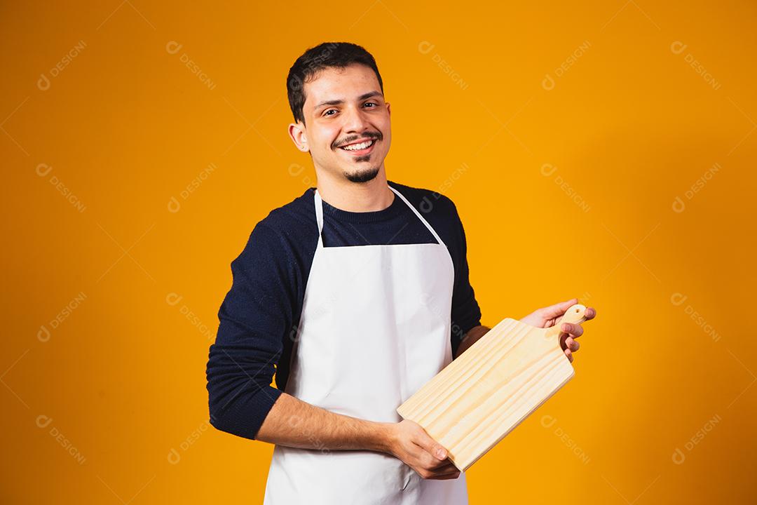homem de avental branco, segurando uma tábua de cortar.