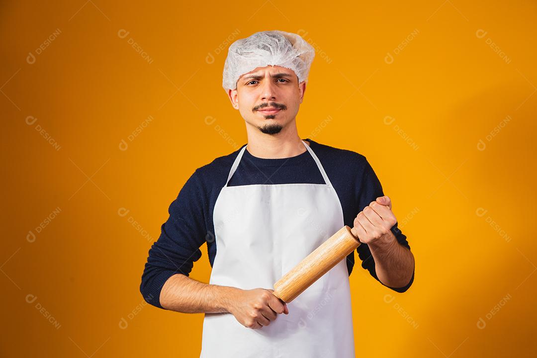 Fabricante de pizza de menino em fundo amarelo, segurando o rolo.