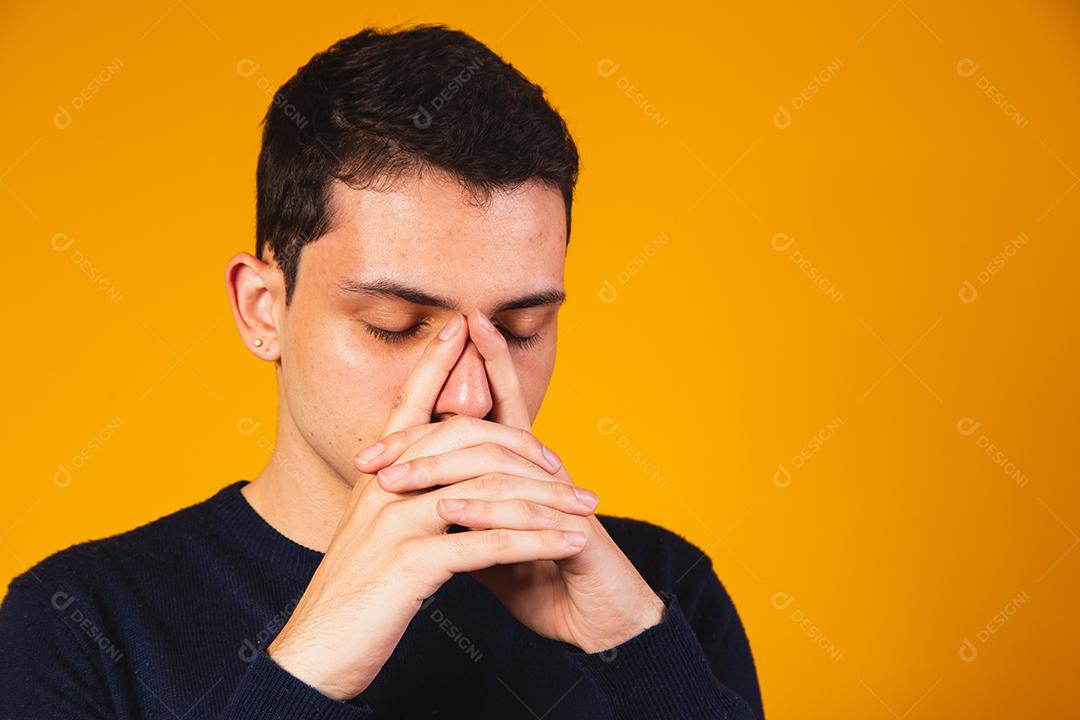 Rapaz nervoso rezando sobre fundo amarelo. menino angustiado falando com deus