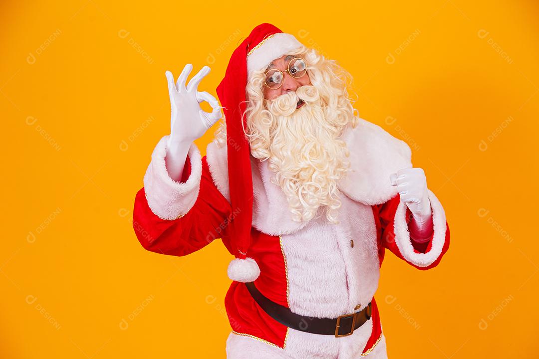 Papai Noel com uma mão fazendo sinal de ok e a outra sim por ter alcançado a meta.