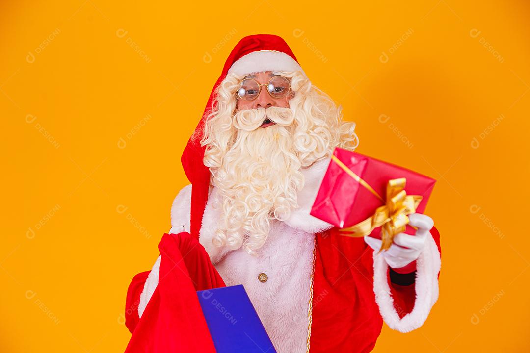 Verdadeiro Papai Noel em fundo amarelo segurando saco com vários c