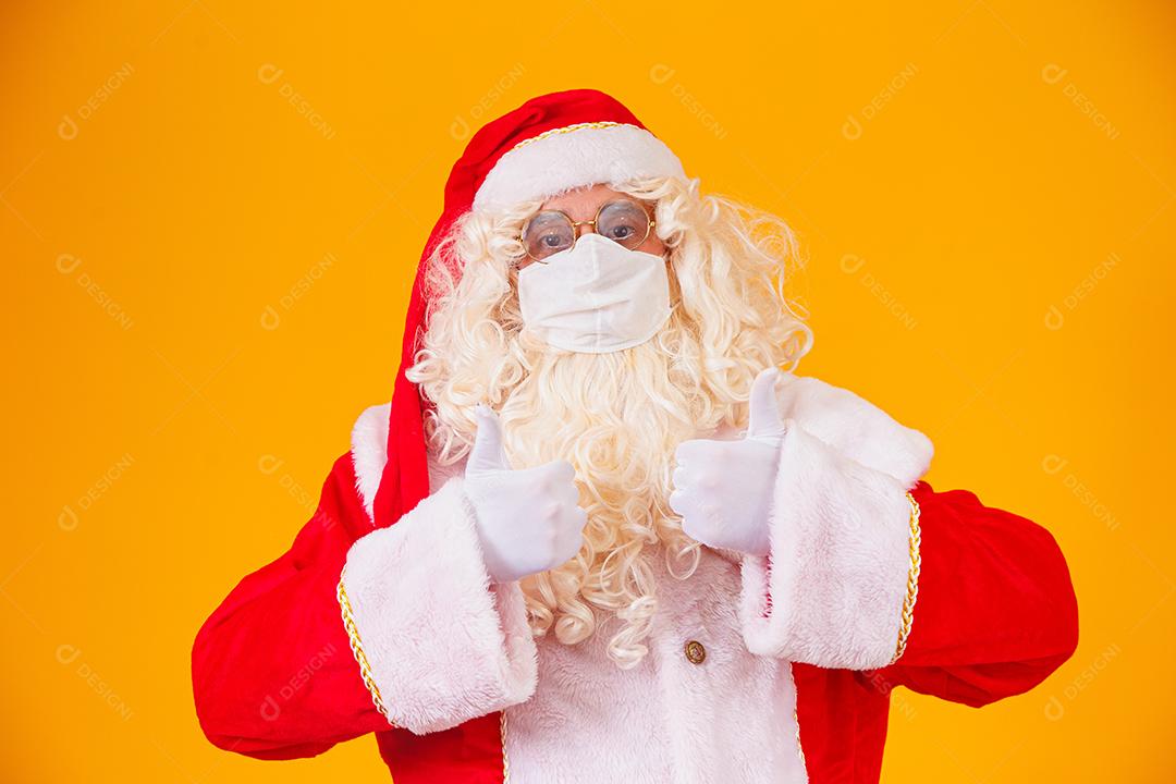 Real Papai Noel em fundo amarelo, usando máscara protetora contra o covid19. Natal com distanciamento social. Covid-19
