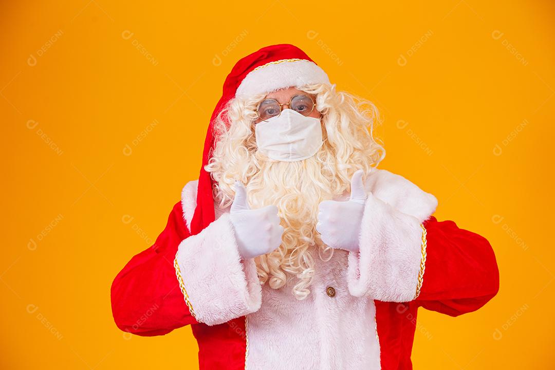 Real Papai Noel em fundo amarelo, usando máscara protetora contra o covid19. Natal com distanciamento social. Covid-19