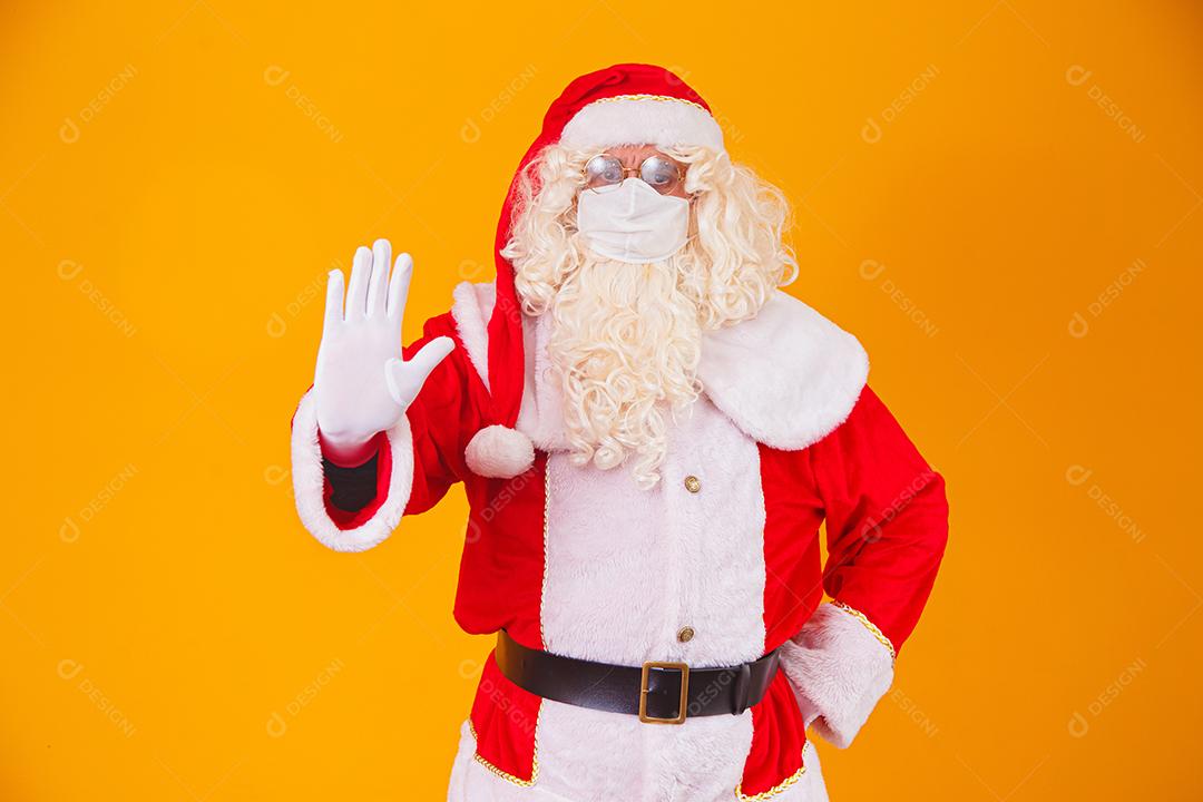 Real Papai Noel em fundo amarelo, usando máscara protetora contra o covid19. Natal com distanciamento social. Covid-19