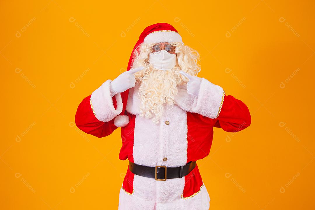 Real Papai Noel em fundo amarelo, usando máscara protetora contra o covid19. Natal com distanciamento social. Covid-19